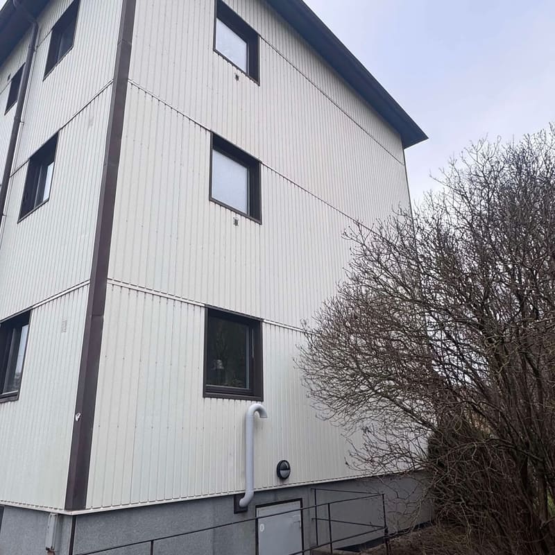 Ljus panelfasad på ett flerbostadshus i tre våningar efter tvätt